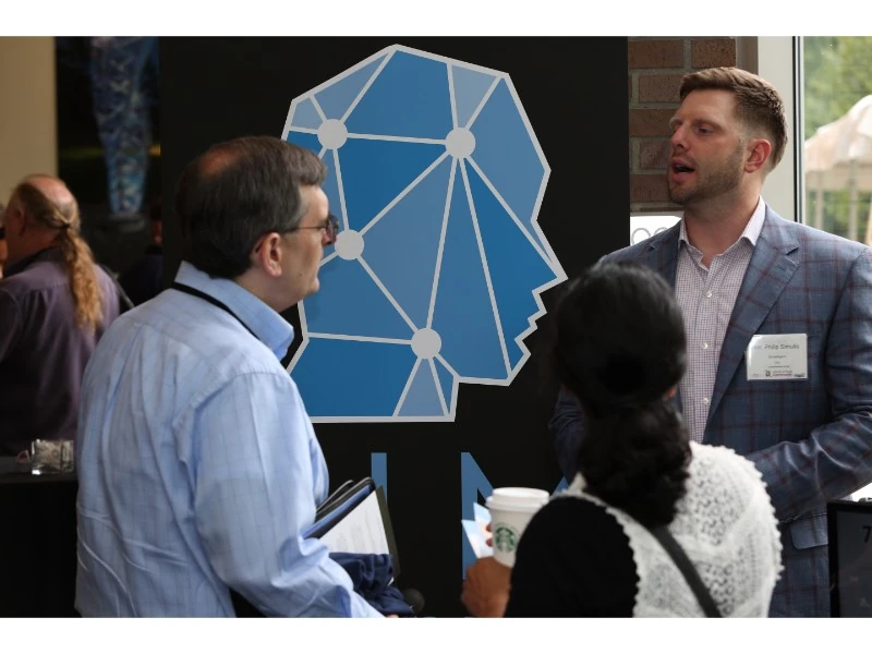 IoT Community event participants in conversation at an industry exhibition.