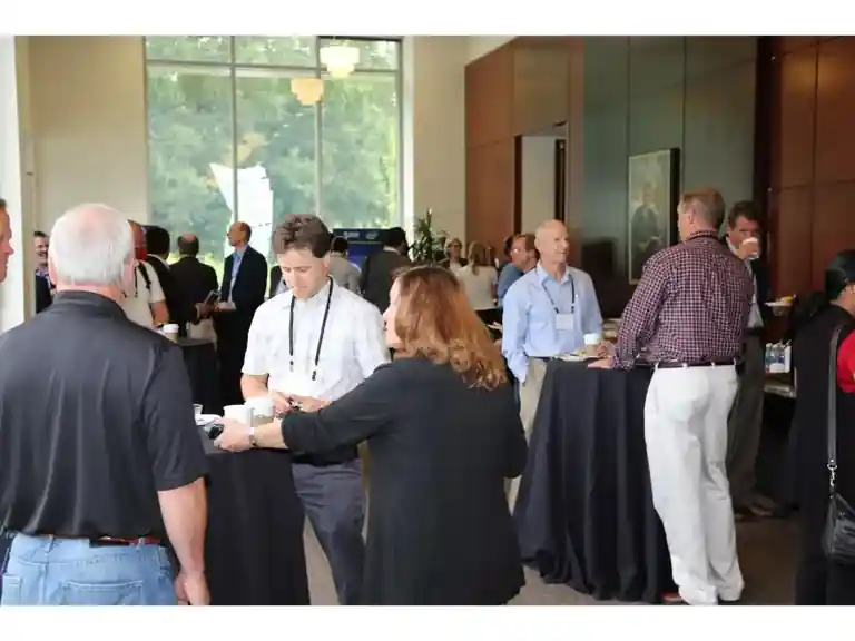 IoT Slam attendees networking around standing tables in a busy reception area.